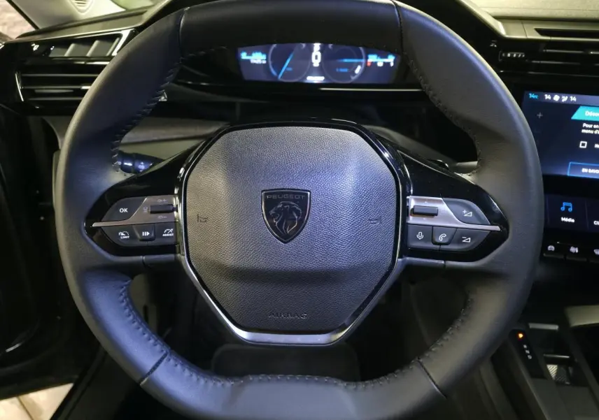 Vue rapprochée du volant cuir noir du Peugeot 408 électrique 2024 avec commandes intégrées et tableau de bord numérique.