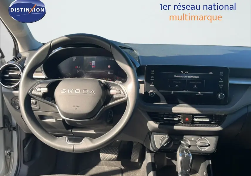Vue intérieure frontale du tableau de bord et volant Skoda Fabia 2025 en Reflex Silver, avec écran tactile et commandes intégrées.