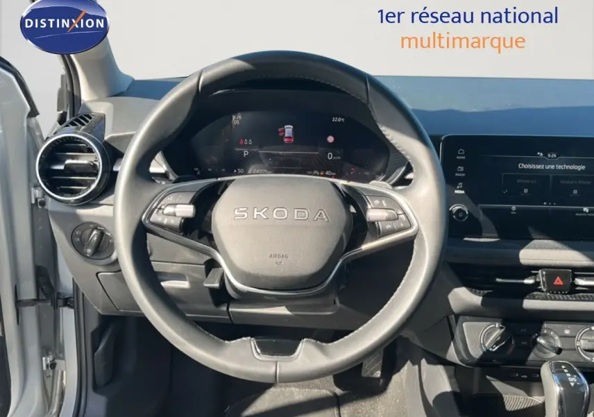 Vue intérieure centrée sur le volant SKODA d'une Fabia 2025, avec tableau de bord numérique et écran tactile.
