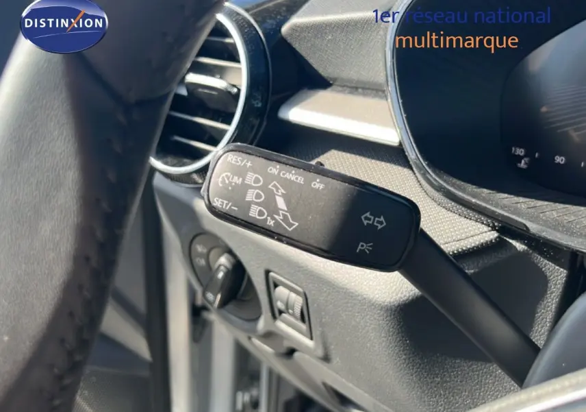 Gros plan sur la commande de régulateur de vitesse à gauche du volant dans l’habitacle gris noir de la Skoda Fabia 2025.