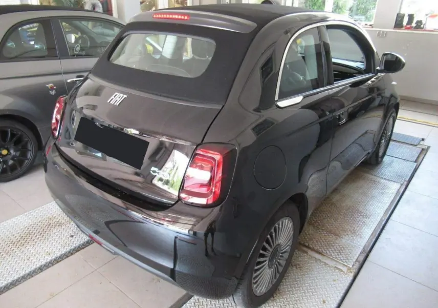 Vue 3/4 arrière droite d'une FIAT 500 Cabriolet électrique noire avec capote noire et jantes alliage 16 pouces.