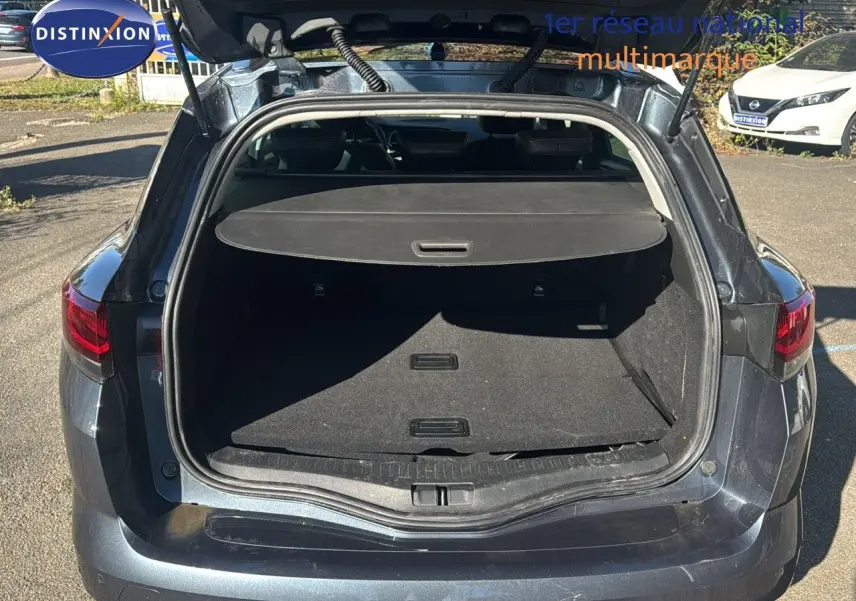 Coffre ouvert vu de l'arrière d'une Renault Mégane Break gris titanium métal, montrant l'espace de chargement.