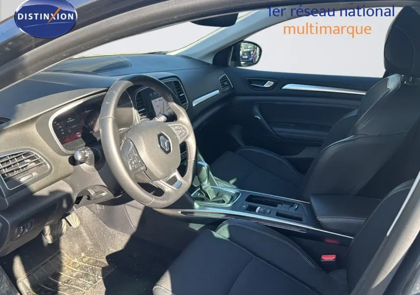 Intérieur de Renault Mégane Break 2024 en vue côté conducteur, sièges noirs et tableau de bord moderne.