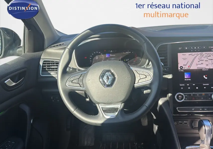 Vue intérieure centrée sur le volant Renault d'une Mégane Break 2024 avec tableau de bord numérique et écran tactile.
