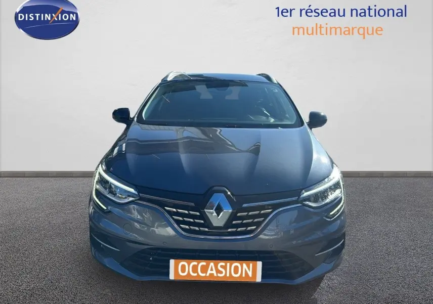 Vue frontale d'une Renault Mégane Break gris titanium métal avec calandre et phares LED allumés.