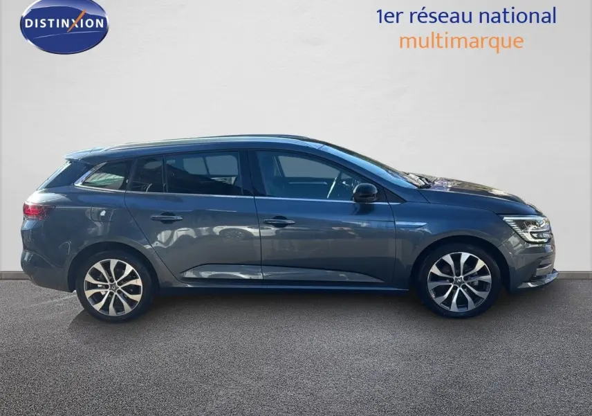 Profil droit d'une Renault Mégane Break gris titanium métal 2024 avec jantes alliage bicolores et vitres teintées.