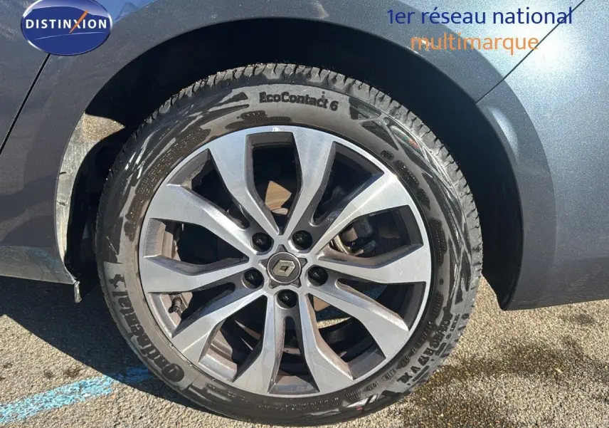 Gros plan sur la roue avant droite d'une Renault Mégane Break gris titanium métal avec jante alliage à dix branches.