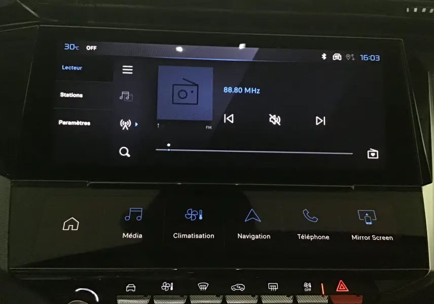 Écran tactile central de la Peugeot 308 gris Sellenium 2025 affichant la radio FM et les commandes multimédia.