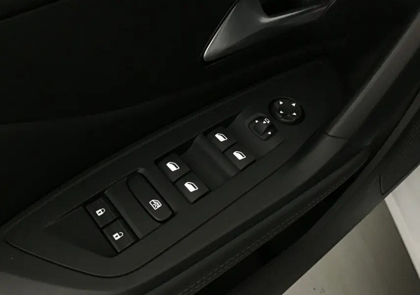 Gros plan sur les commandes des vitres et rétroviseurs côté gauche d'une Peugeot 308 2025 gris Sellenium.