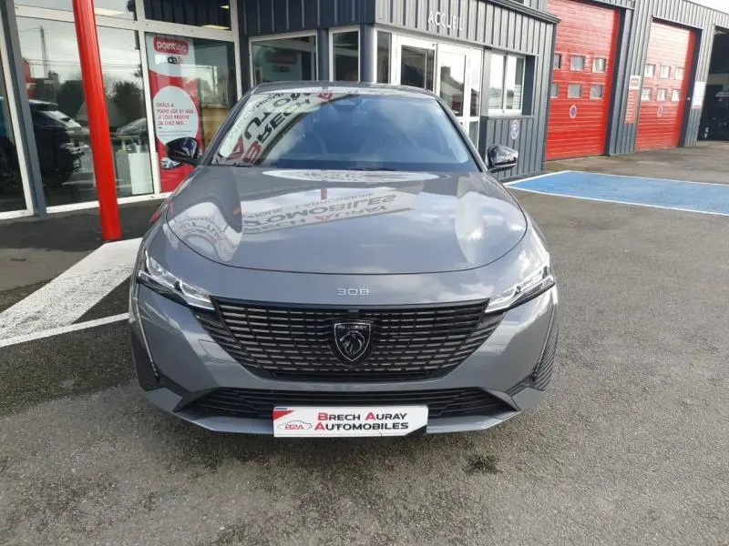 Vue frontale d'une Peugeot 308 2024 gris Sélénium avec calandre noire et logo lion central bien visible.
