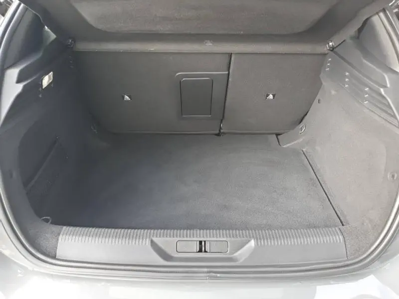 Coffre ouvert de la Peugeot 308 1.5 BlueHDi gris Sélénium, montrant l'espace de chargement et la banquette arrière rabattable.
