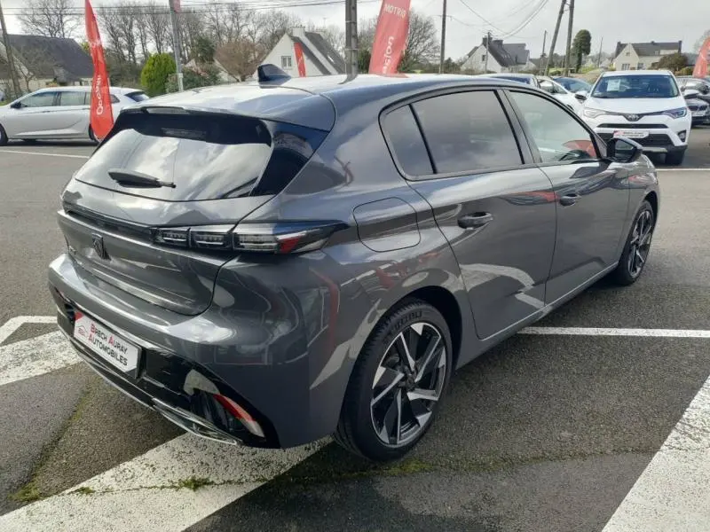 Vue 3/4 arrière droite d'une Peugeot 308 gris Sélénium avec vitres surteintées et jantes alliage modernes.