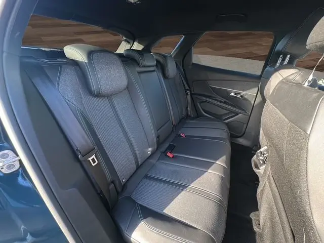 Vue latérale droite de l'intérieur arrière du Peugeot 3008 2023 bleu Célèbes, sièges tissu noir avec surpiqûres blanches.