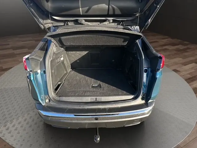 Coffre ouvert en vue arrière d’un Peugeot 3008 bleu Célèbes 2023, montrant un espace de chargement spacieux et propre.