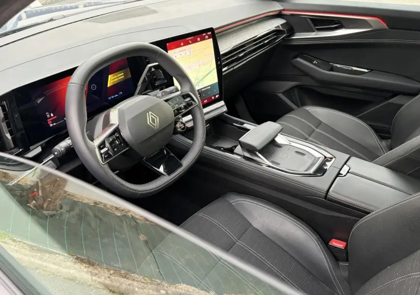 Vue intérieure côté conducteur du Renault Austral 2025 avec tableau de bord numérique et sellerie noire à surpiqûres grises.