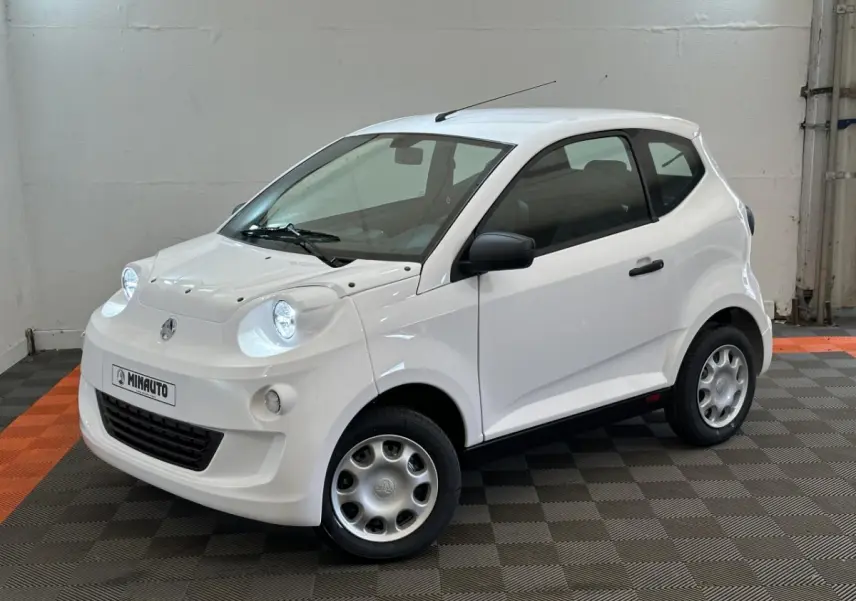 Vue 3/4 avant droit d'une Aixam Minauto E Access blanche avec rétroviseur caméra côté conducteur.