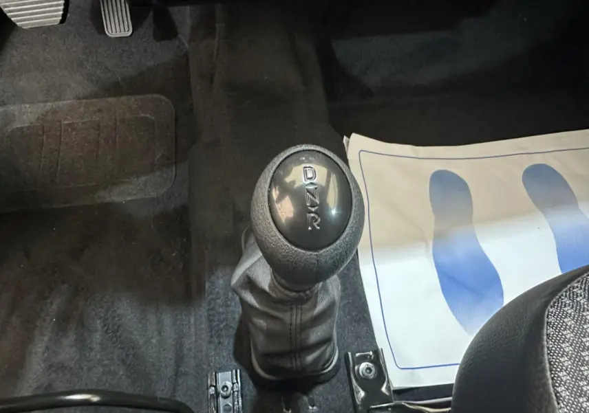 Gros plan sur le levier de vitesses automatique noir de l'AIXAM MINAUTO E ACCESS 2026, intérieur avec tapis et pédales visibles.