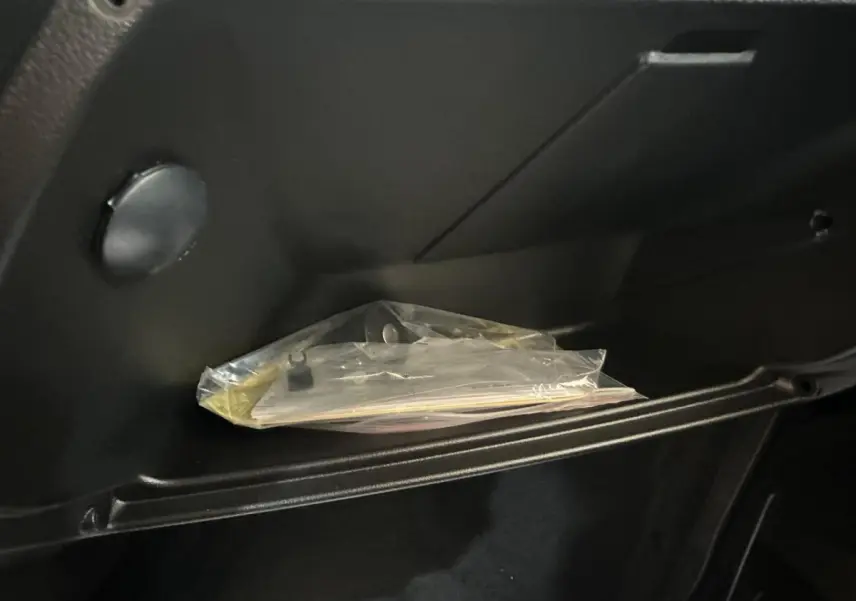 Gros plan sur la boîte à gants noire de l'AIXAM MINAUTO E ACCESS 2026 avec documents plastifiés à l'intérieur.