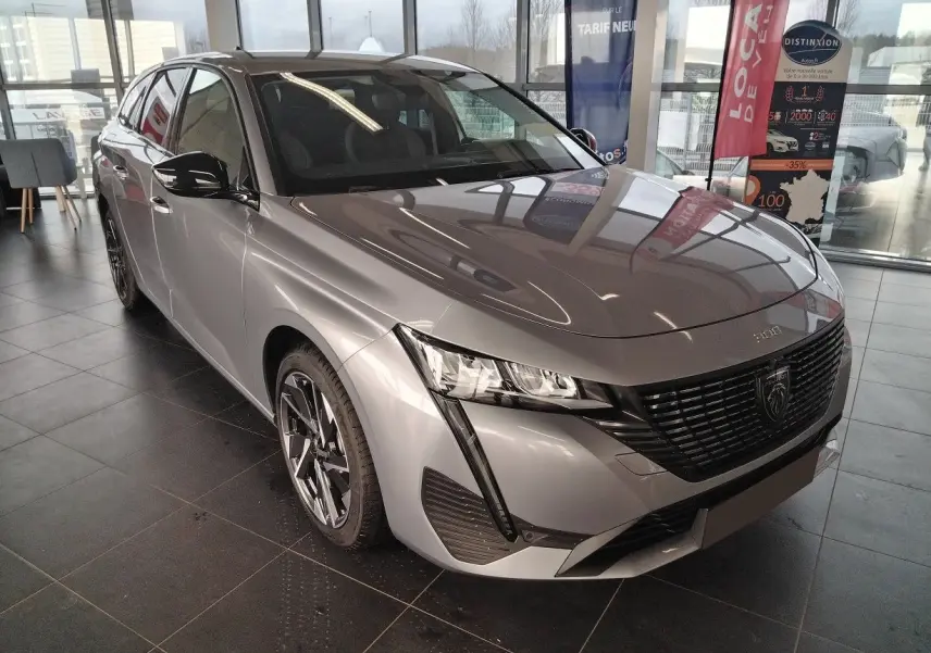 Peugeot 308 SW Hybrid gris Artense vue 3/4 avant gauche en showroom avec jantes bi-ton et calandre noire.