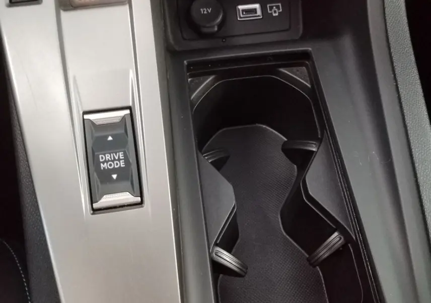 Vue rapprochée de la console centrale gris Artense du Peugeot 308 SW Hybrid avec sélecteur de mode de conduite et porte-gobelets.