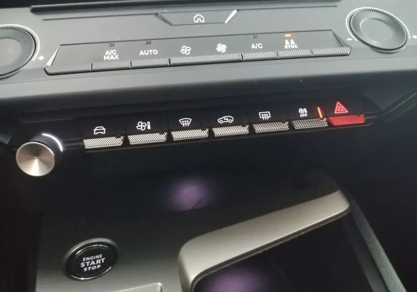 Vue rapprochée du tableau de bord de la Peugeot 308 SW Hybrid 2025, boutons de commande éclairés et bouton start/stop visible.