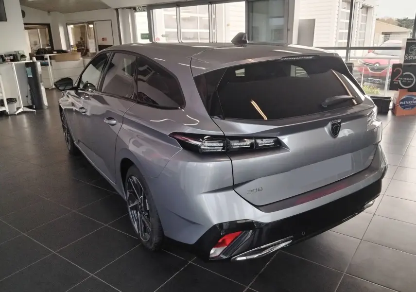Vue 3/4 arrière droit d'une Peugeot 308 SW Hybrid gris Artense en showroom, avec feux arrière LED et jantes biton.