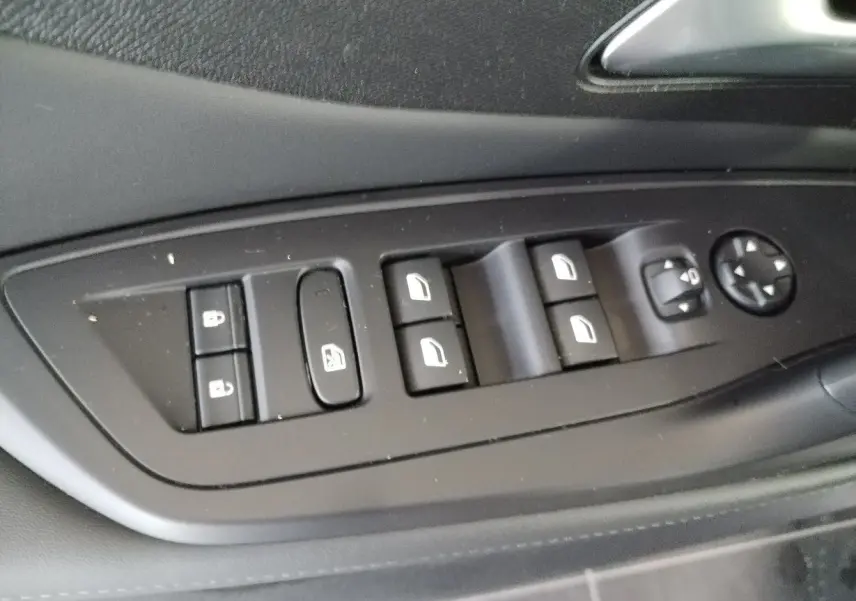 Gros plan sur les commandes des vitres et des rétroviseurs côté conducteur du Peugeot 308 SW Hybrid 2025, finition noire.