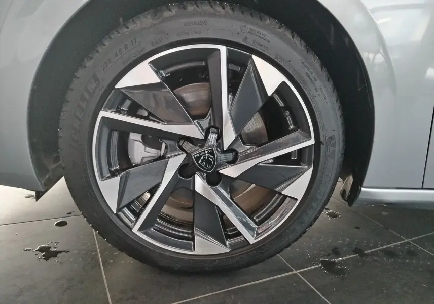Gros plan sur la jante alliage bicolore noire et argentée d'une Peugeot 308 SW Hybrid 145 gris Artense.