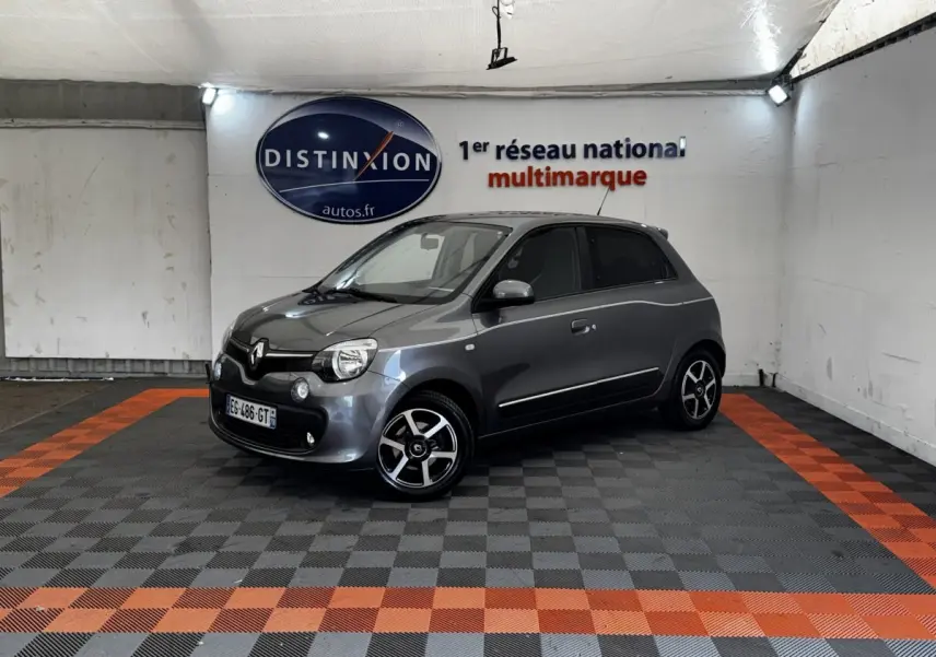 Renault Twingo Intense Energy gris foncé vue 3/4 avant droit dans un garage avec sol à damiers gris et orange.