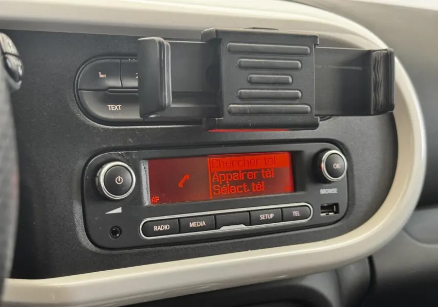 Console centrale avec écran radio rouge et support téléphone dans une Renault Twingo gris foncé, vue intérieure rapprochée.
