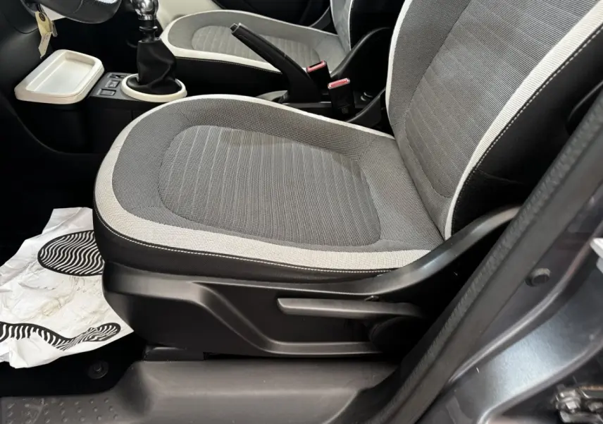 Vue rapprochée du siège avant droit gris clair avec contours sombres et levier de frein à main d’une Renault Twingo 2016.