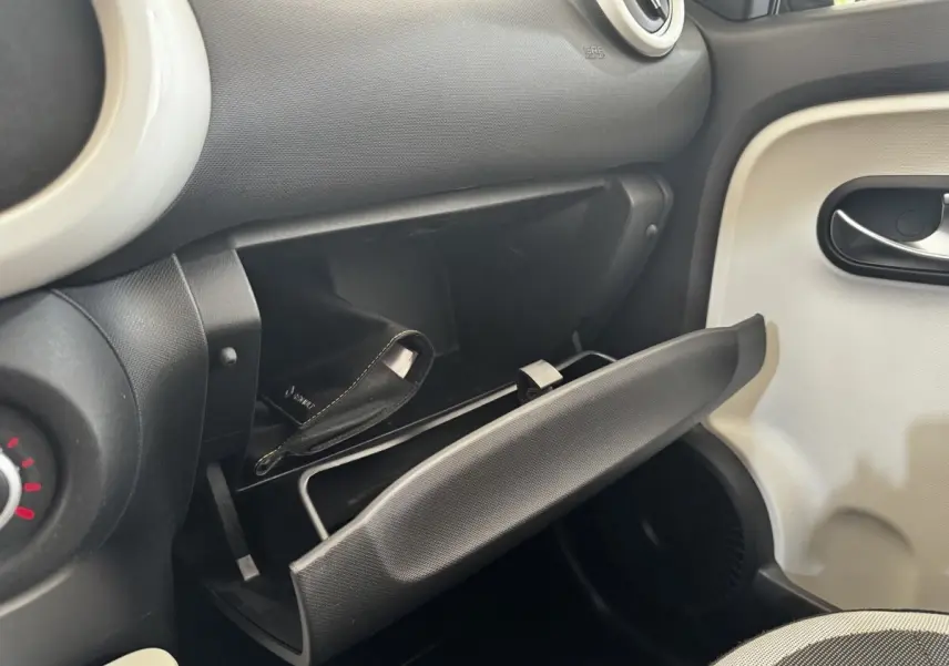 Vue intérieure côté passager de la Renault Twingo Intense Energy TCe 90 2016, boîte à gants ouverte avec pochette noire visible.