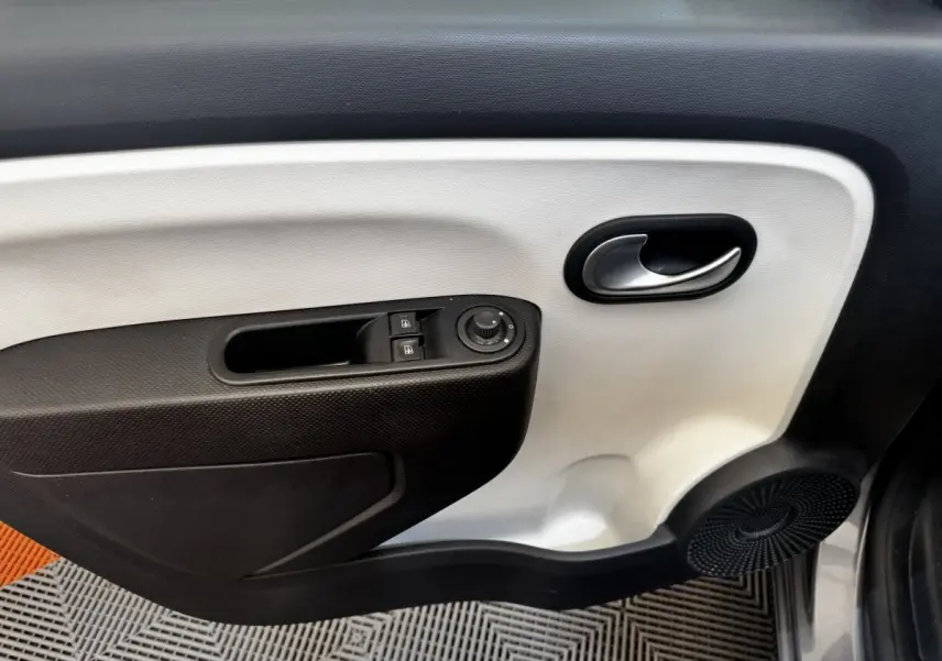 Gros plan sur la porte intérieure côté conducteur de la Renault Twingo gris foncé, avec commandes de vitres et rétroviseurs.