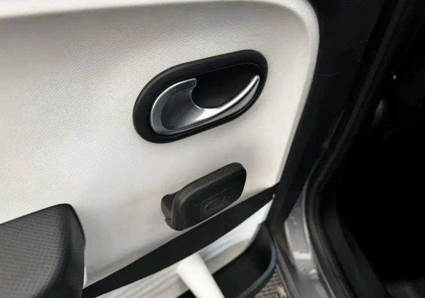 Poignée de porte intérieure côté droit de Renault Twingo gris foncé, avec ouverture de coffre manuelle visible.