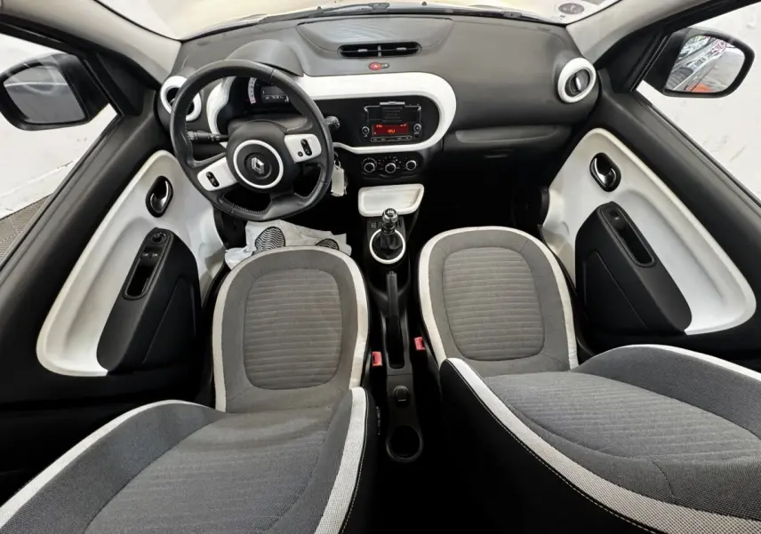 Vue intérieure avant de la Renault Twingo gris foncé, montrant le tableau de bord, volant cuir et sièges tissu gris.