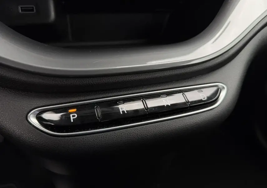 Gros plan sur la commande de boîte automatique avec boutons P, R, N, D éclairé en orange dans une Fiat 500 électrique blanche.