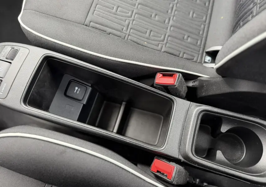 Gros plan sur la console centrale et les sièges noirs avec surpiqûres blanches de la Fiat 500 électrique 2024.