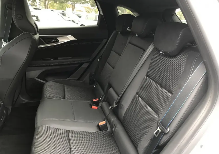 Vue intérieure côté droit des sièges arrière noirs avec surpiqûres bleues du Renault Austral blanc 2025 finition Esprit Alpine.