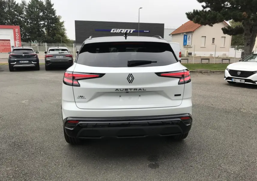Vue arrière d'un Renault Austral blanc bi-ton avec feux arrière LED et logo central sur un parking extérieur.