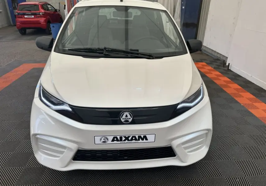 Vue de face d'une Aixam Ambition E City Pack blanche 2026 avec calandre noire et phares LED distinctifs.