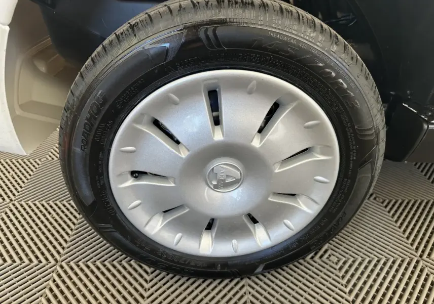 Gros plan sur la roue avant droite d'une Aixam Ambition E City Pack blanche avec enjoliveur argenté et logo central.