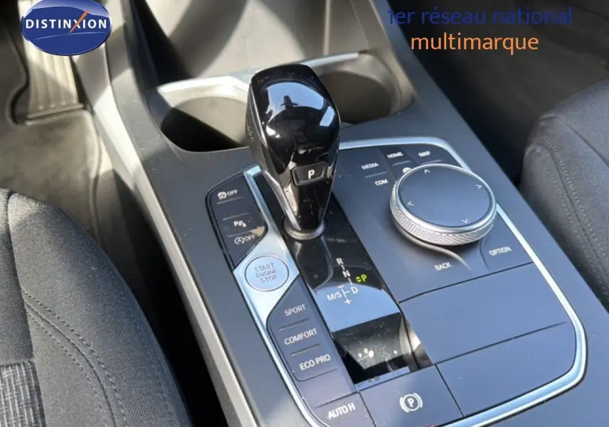 Vue rapprochée de la console centrale de la BMW Série 1 116i 2022 avec levier de vitesses noir brillant et commandes multifonctions.