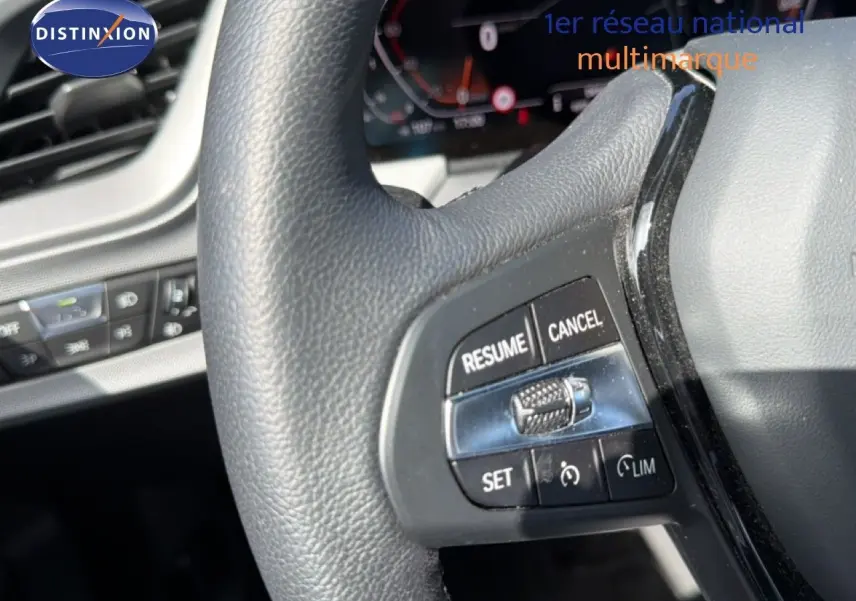 Gros plan sur le volant noir de la BMW Série 1 116i 2022, mettant en valeur les commandes de régulateur de vitesse.