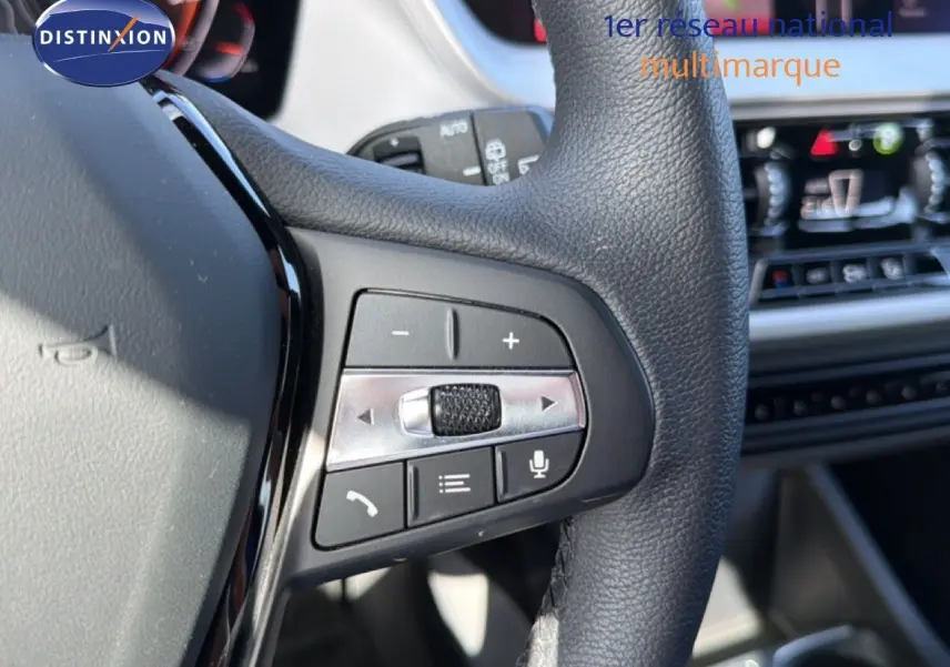 Gros plan sur les commandes au volant en cuir noir de la BMW Série 1 116i 2022, avec tableau de bord flou en arrière-plan.