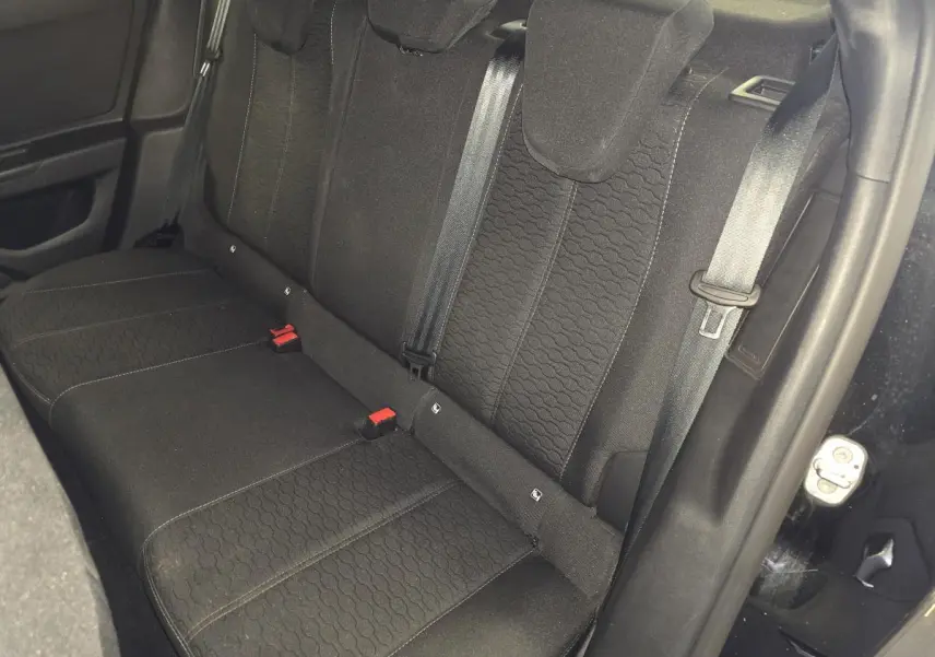 Vue intérieure de la banquette arrière noire de l'Opel Mokka 2025, avec ceintures de sécurité visibles.