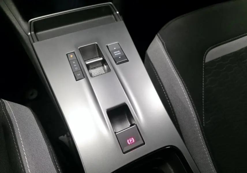 Vue rapprochée de la console centrale grise avec sélecteur de boîte automatique et frein à main électrique dans un Opel Mokka noir.