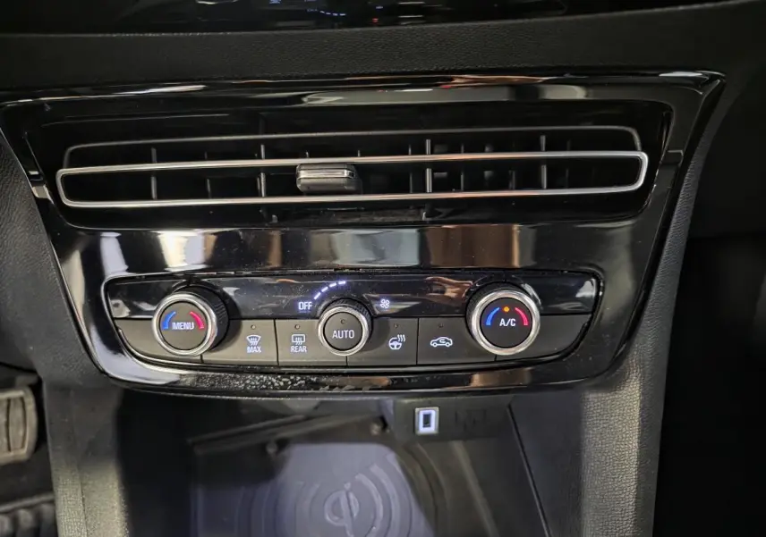 Détail de la console centrale noire de l’Opel Mokka 2025 avec commandes climatisation et recharge smartphone sans fil.