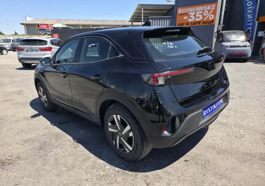 Opel Mokka noir vue 3/4 arrière droit, avec jantes bicolores et toit couleur carrosserie sur parking extérieur.