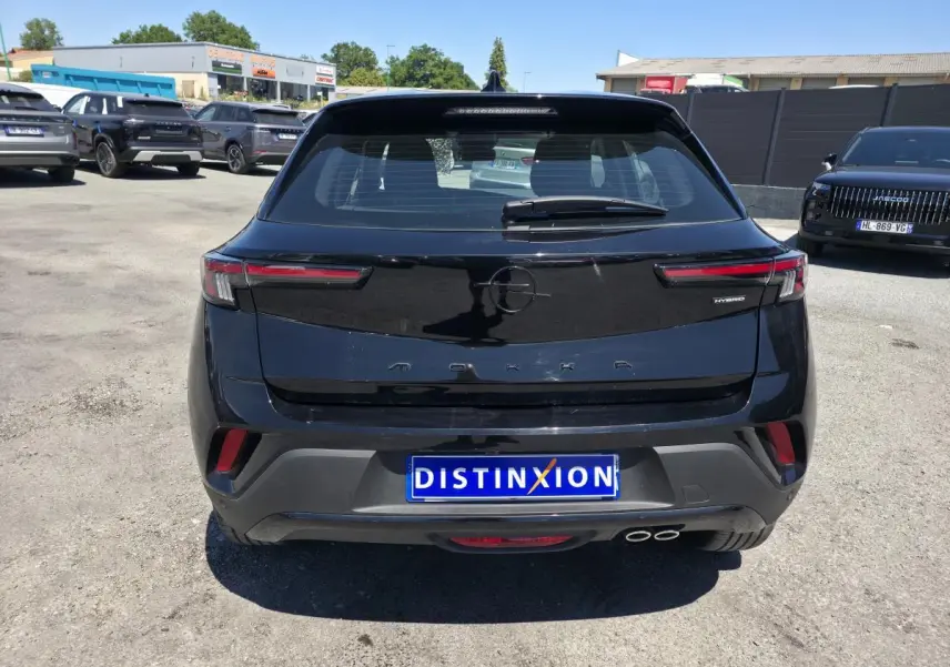 Vue arrière d'un Opel Mokka noir 2025 avec double sortie d'échappement et logo "Hybrid" à droite.