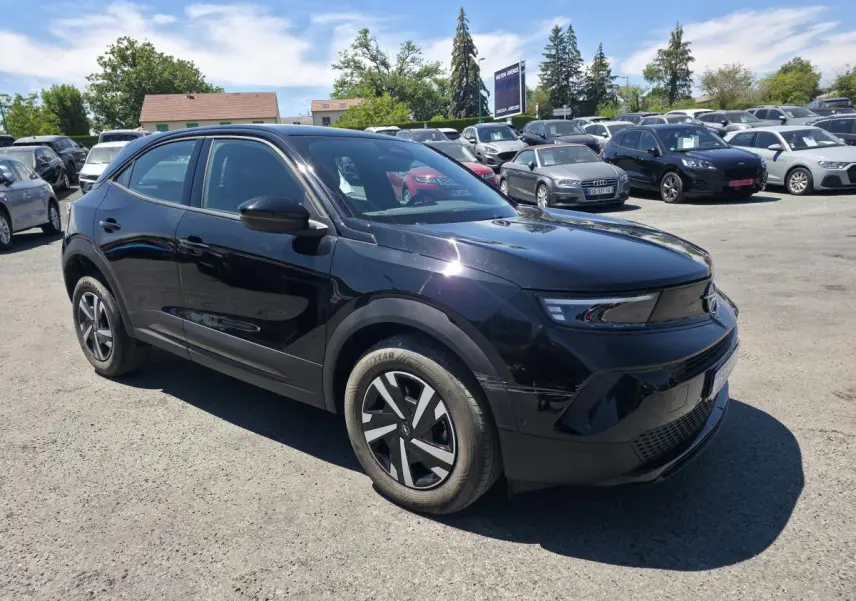 Vue 3/4 avant droite d'un Opel Mokka noir avec calandre Vizor noire et jantes en acier 16 pouces au parking.